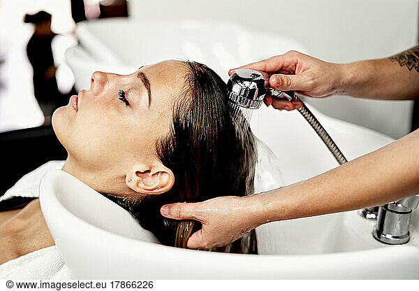 Hairstylist Washing Hair Of Client Over Sink