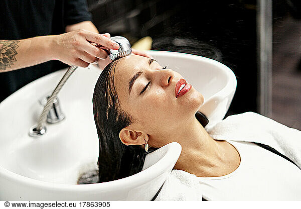 Hairstylist Washing Hair Of Female Customer