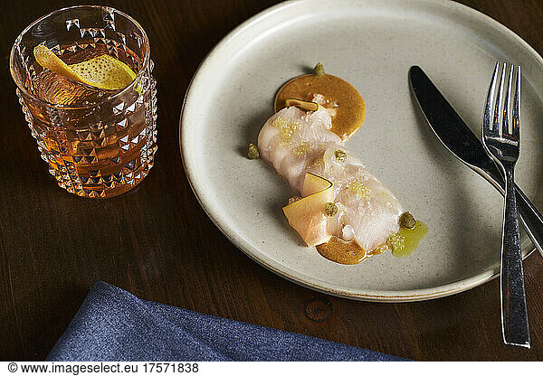 Hamachi crudo with a caper citrus sauce and whiskey old fashioned.