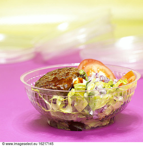 Hamburger with mixed salad in plastic bowl, close-up