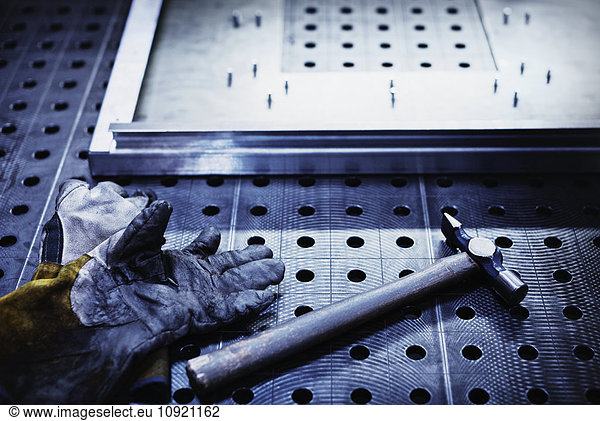 Hammer and gloves on steel in steel factory