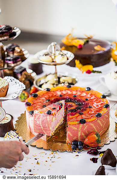 Hand der Person  die ein Stück Erdbeerkuchen nimmt