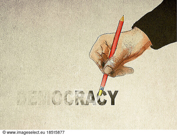 Hand holding pencil and erasing democracy text