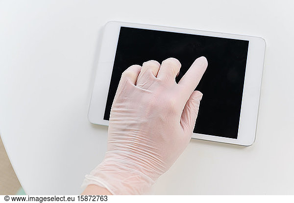 Hand in protective glove using tablet