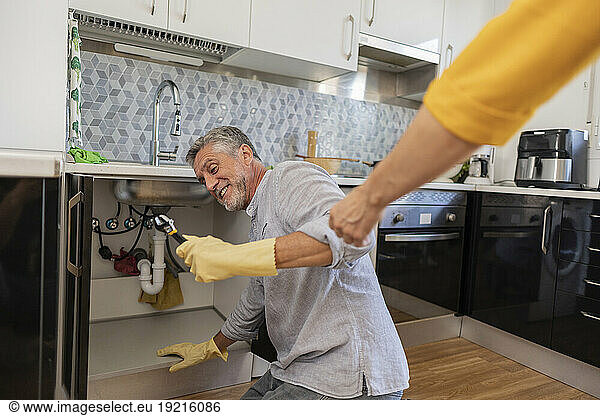 Hand of assisting man repairing faucet in kitchen at home