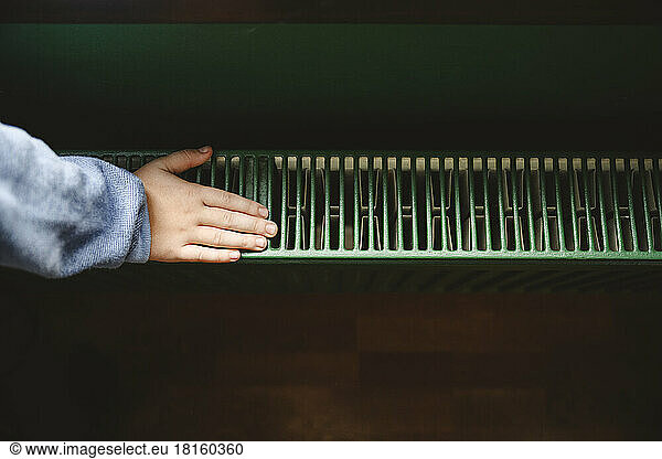 Hand of boy touching radiator at home