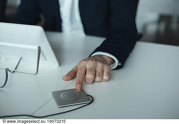 Hand of businessman pushing button at desk