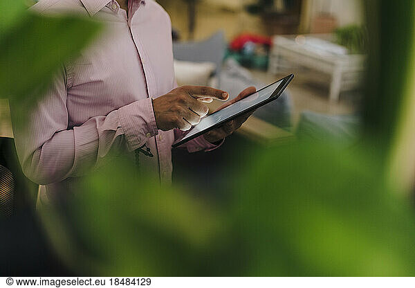 Hand of businessman touching tablet PC screen in office