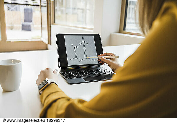 Hand of businesswoman drawing wind turbine on tablet PC with digitized pen