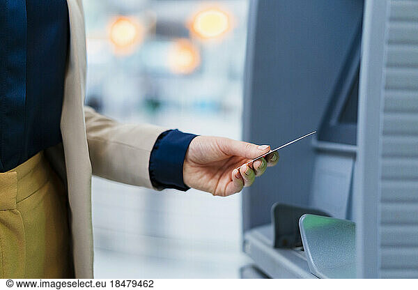Hand of businesswoman holding credit card near ATM