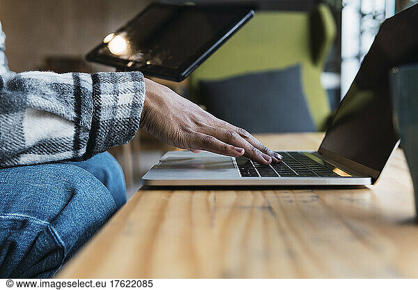 Hand of businesswoman typing on laptop in coffee shop