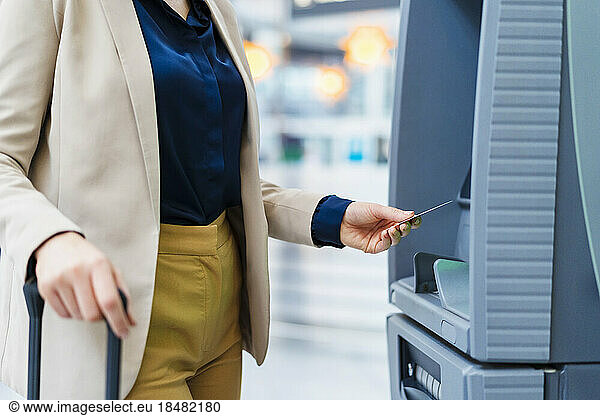 Hand of businesswoman using credit card at ATM