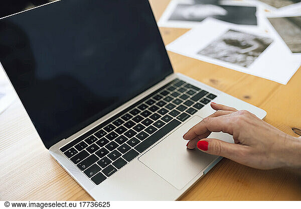 Hand of businesswoman using laptop on table at home
