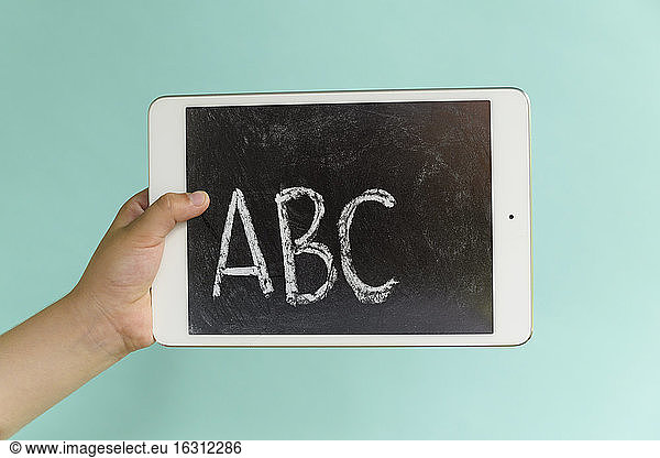 Hand of child (6-7) holding digital tablet showing alphabet