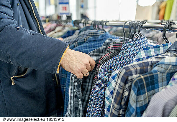 Hand of man choosing clothes on rack