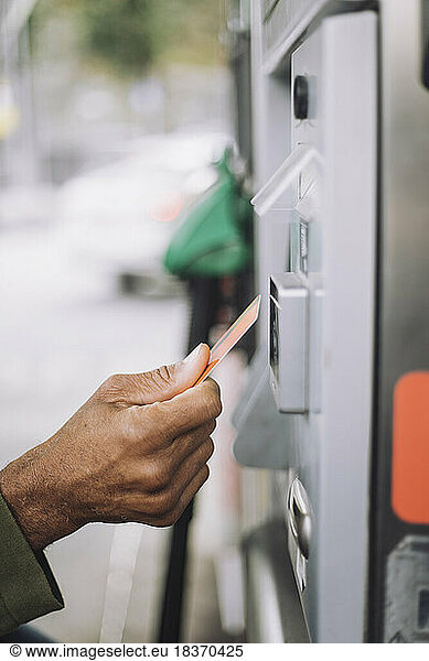 Hand of man doing payment via credit card at gas station
