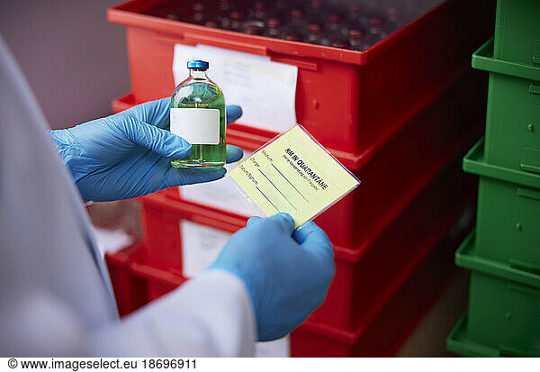 Hand of scientist examining chemical bottle in microbiological laboratory