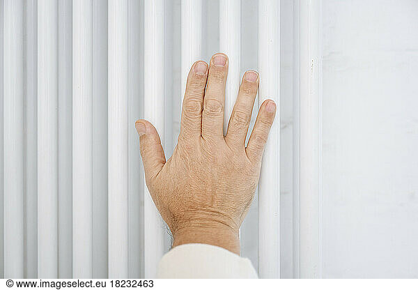 Hand of senior man touching radiator at home