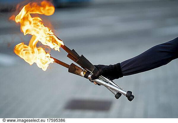 Hand of street artist holding flaming torches