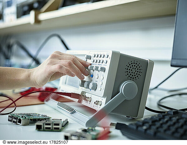 Hand of technician adjusting oscilloscope in electronic laboratory