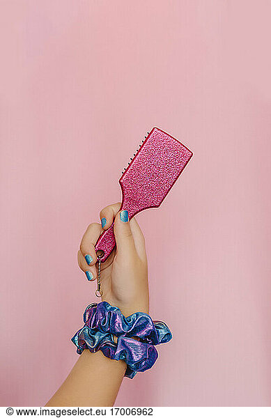 Hand of teenage girl holding pink hair brush