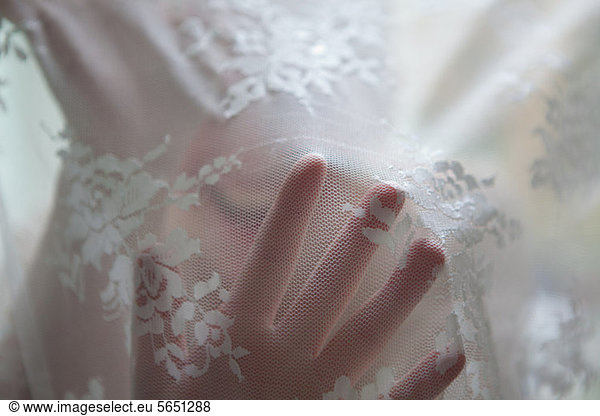 Hand of woman behind lace curtain