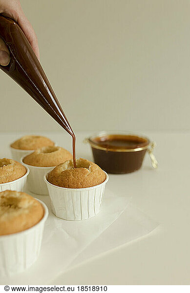 Hand of woman filling cupcakes with salted caramel
