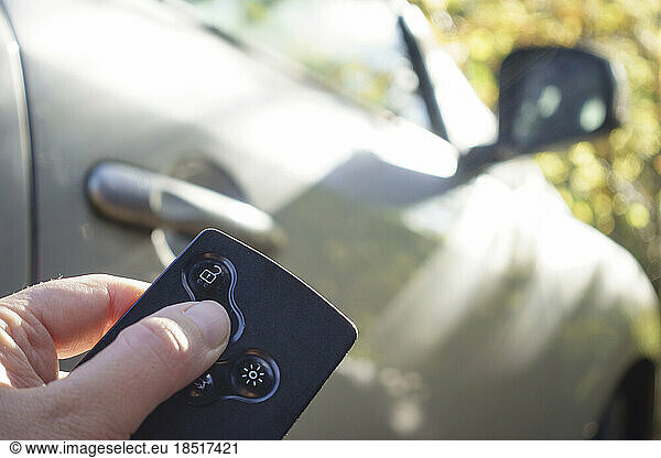 Hand of woman locking car with key card