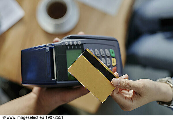 Hand of woman paying through credit card at cafe