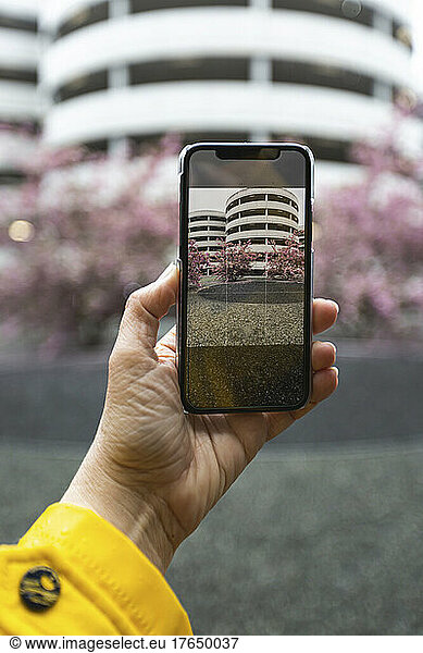 Hand of woman taking smart phone photo of parking garage