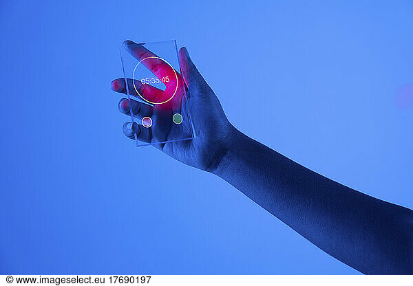 Hand of woman with stopwatch on futuristic transparent smart phone against blue background
