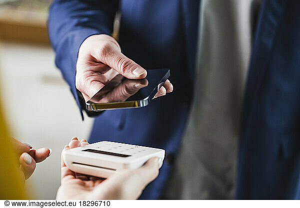 Hand of young businessman paying through smart phone
