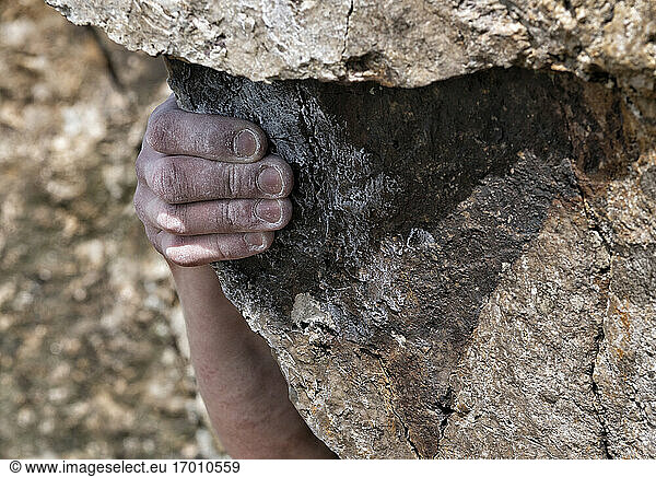 Hand of young man climbing boulder