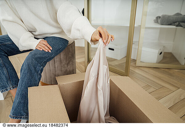 Hand of young woman putting clothes in box for recycle