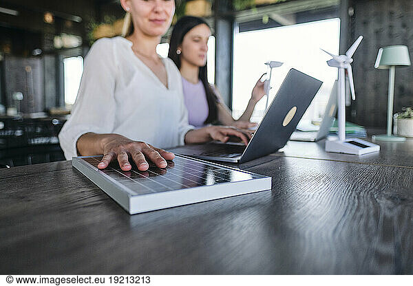 Hand of young woman testing solar panel while working at coworking space