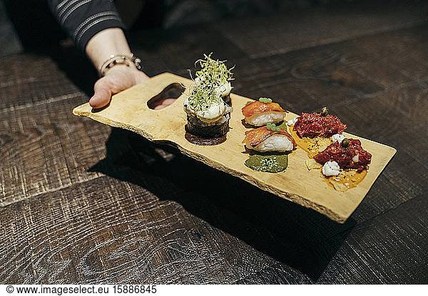 Hand serving Spnaish gourmet food on a board