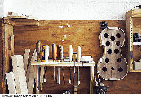 Hand tools and incomplete violin hanging in workshop