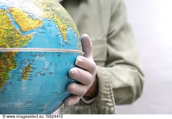 Hand with protective glove  touching globe