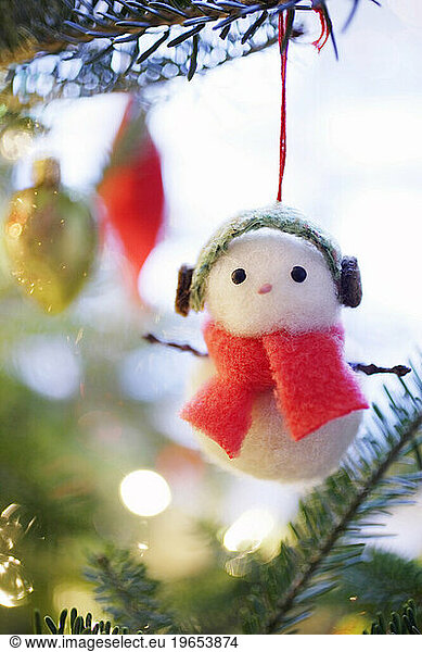Handcrafted Snowman ornament hanging from a Christmas tree branch.