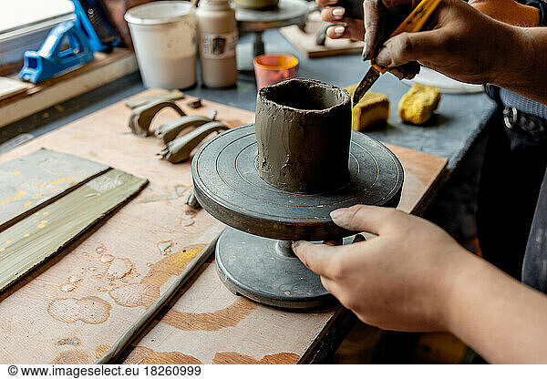 Hands Crafting Cup on a Pottery Wheel in Ceramic Studio