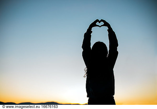 Hands form a Heart for Love Silhouette with Sunset or Sunrise