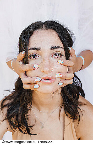 Hands massaging face of young woman