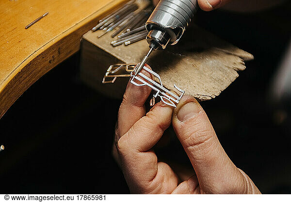 hands of a jeweler working with a file on a blank of silver jewelry