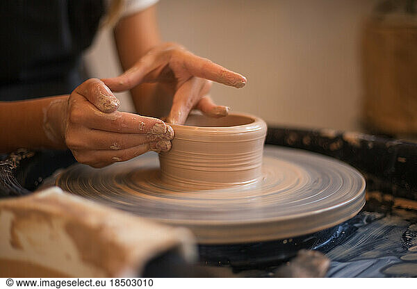 Hands of a little girl in the process of sculpting a mug with ce