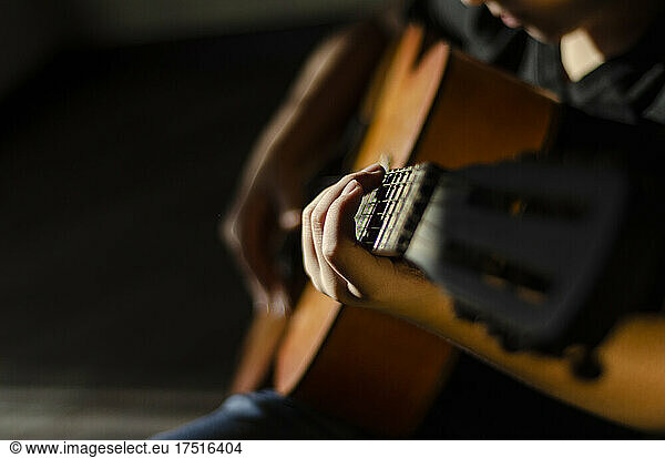 hands of a teen play the guitar