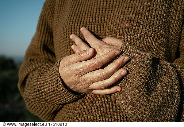 Hands of a woman wearing brown pullover
