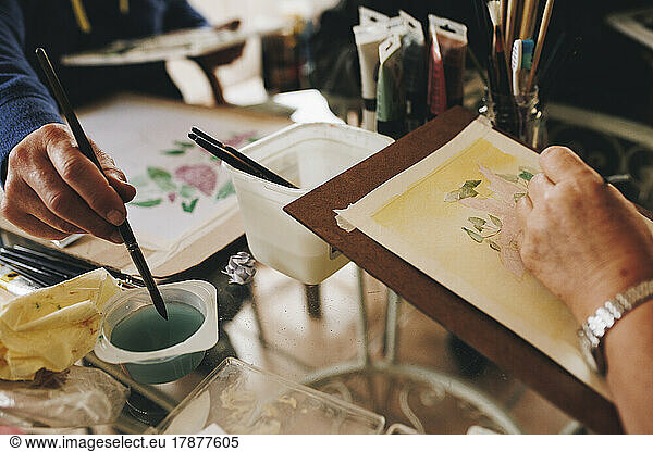Hands of artists painting with paintbrush at home