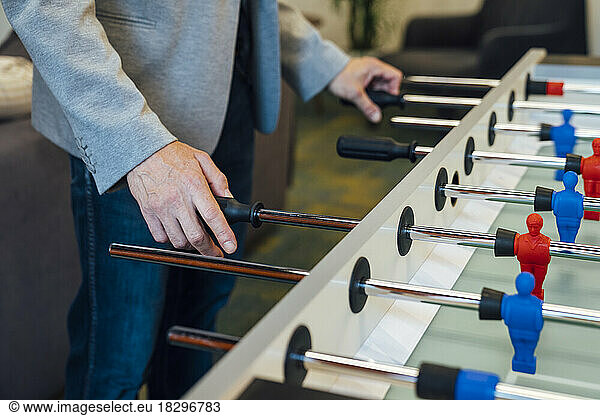 Hands of businessman playing foosball in office