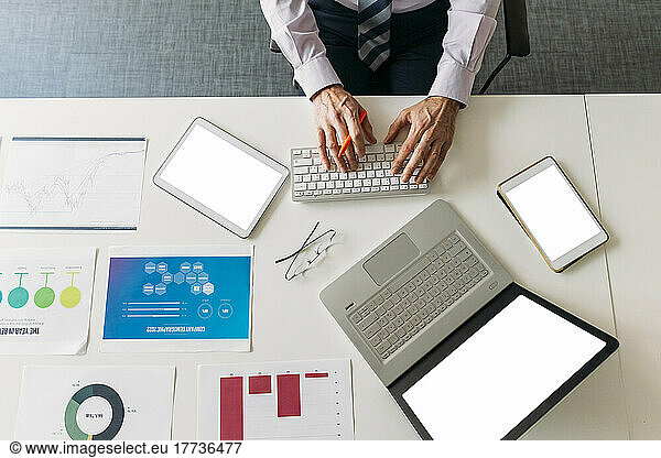 Hands of businessman typing on keyboard at desk in office