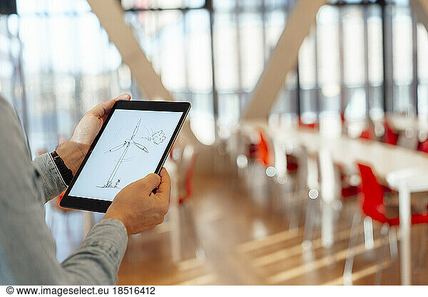 Hands of businessman with wind turbine design on tablet PC in office